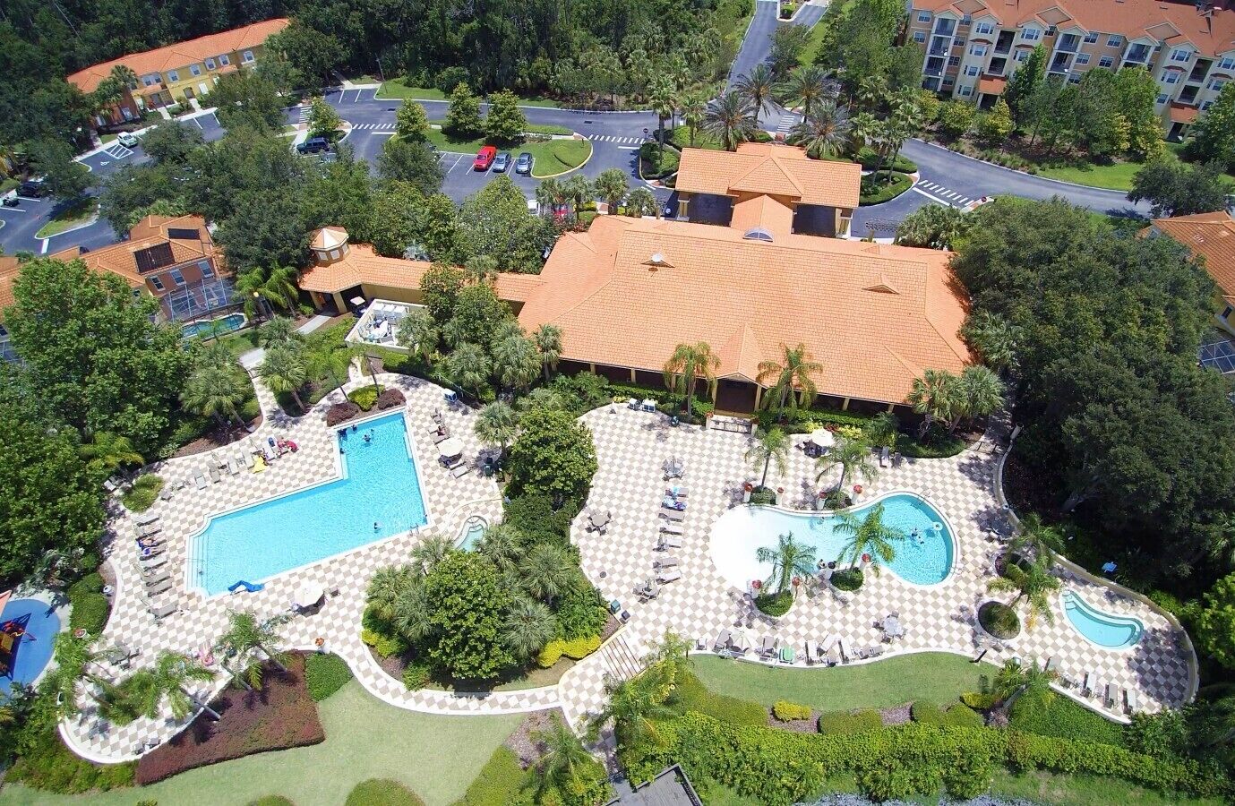 A resort with multiple swimming pools, landscaped areas, and a parking lot.