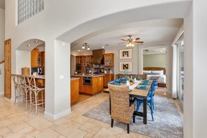 A spacious kitchen with an island, wooden cabinets, and a dining area with blue chairs and a table set for six. - River Villa with pool and spa ~ Best Swimming Hole (Three Rivers)