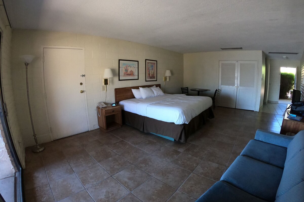 Ein Hotelzimmer mit Bett, Nachttisch, Lampe und Stuhl.