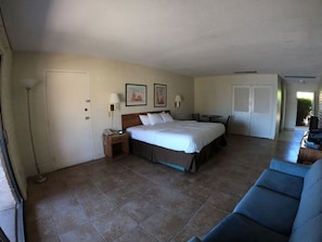 Ein Hotelzimmer mit Bett, Nachttisch, Lampe und Stuhl.
