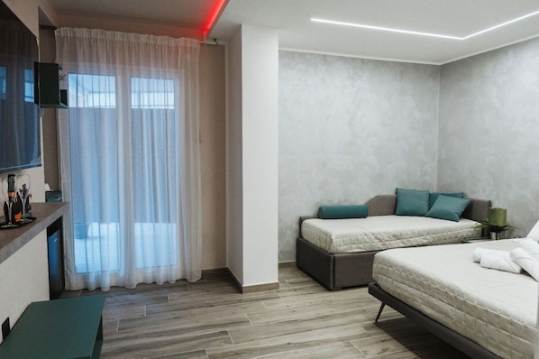 A modern hotel room with a bed, a desk, and a TV. - Sindis Rooms (Palermo)
