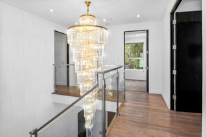 A modern interior with a grand chandelier, a glass railing, and a wooden floor. - ৎ୭Luxury Hollywood Hills | 5BR + Poolৎ୭ (Los Angeles)
