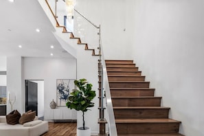 Ein modernes Interieur mit einer Holztreppe, einer weißen Wand und einer Topfpflanze.