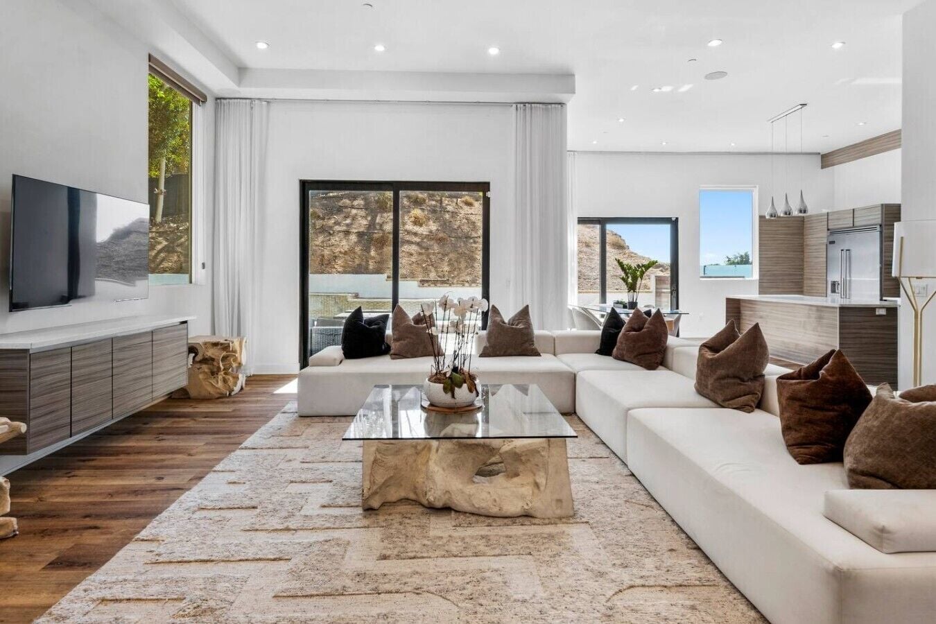 A modern living room with a large sofa, a coffee table, and a flat-screen TV.