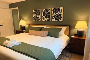 A neatly made bed with a green bedspread and pillows, flanked by two bedside lamps on wooden nightstands. - North Hills Raleigh Retreat (Raleigh)