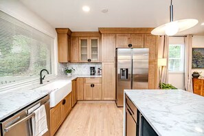 A modern kitchen with wooden cabinets, a stainless steel refrigerator, and a marble countertop. - North Hills Raleigh Retreat (Raleigh)