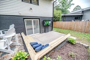 A backyard with a wooden deck, outdoor seating, and a small garden area. - North Hills Raleigh Retreat (Raleigh)