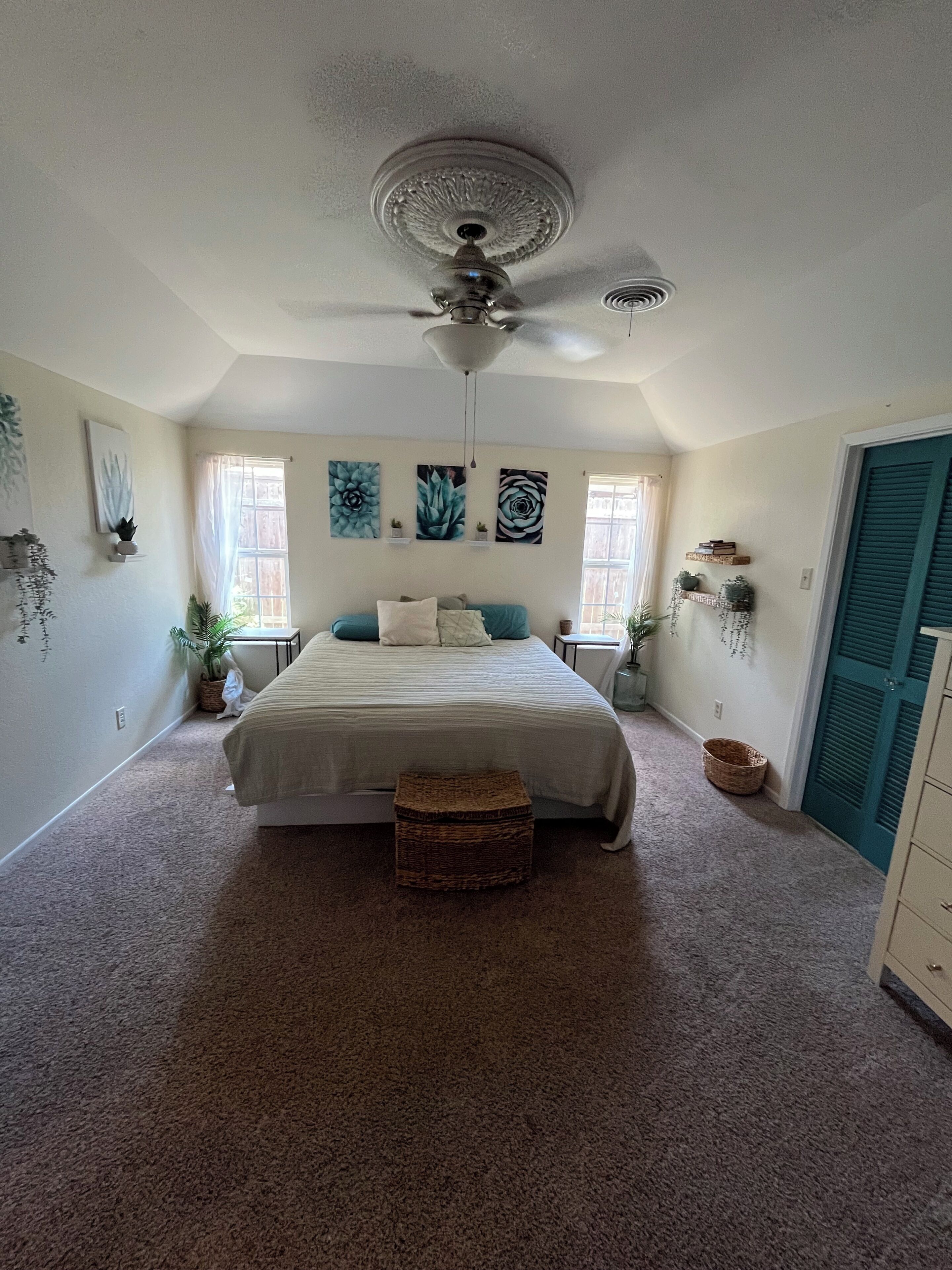 A bedroom with a bed, a ceiling fan, and artwork on the walls.