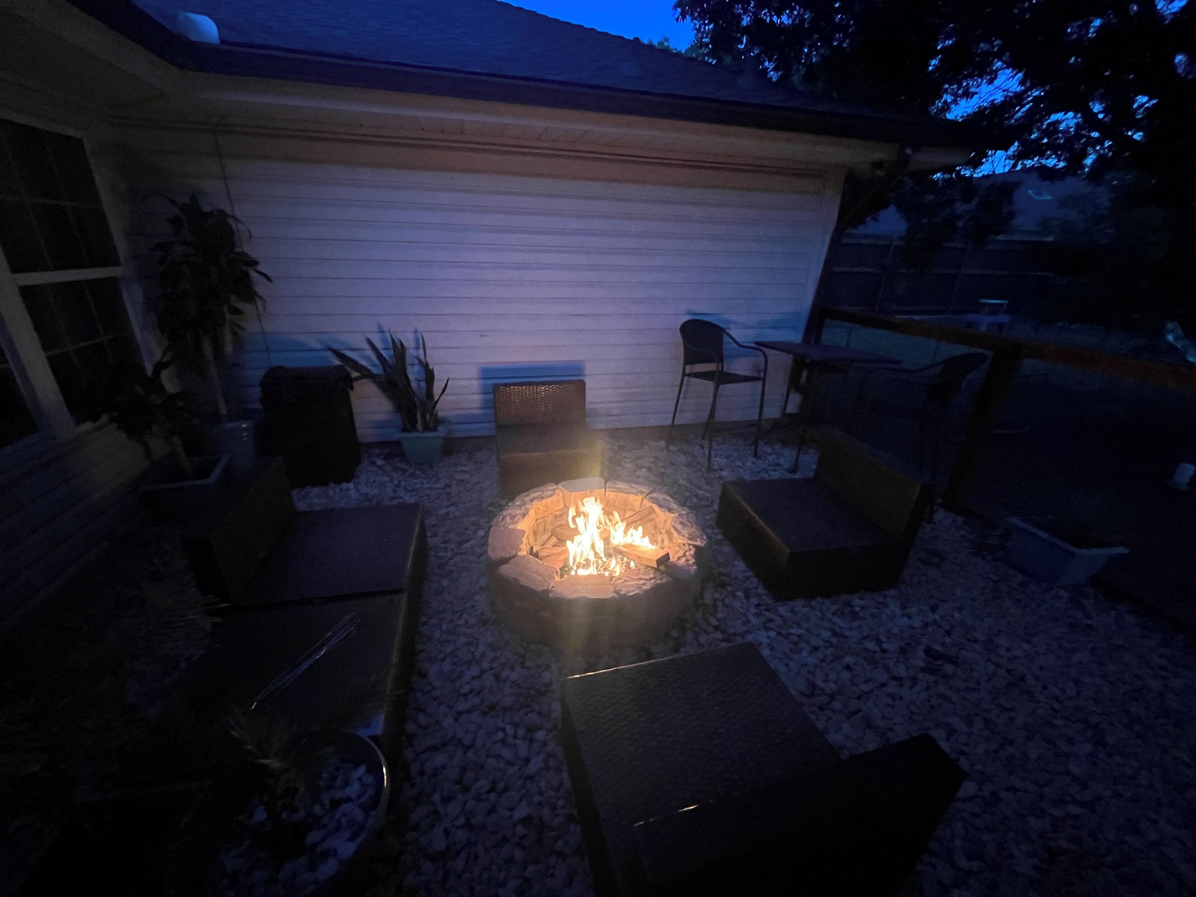 Un patio con una chimenea, asientos y una planta en maceta.