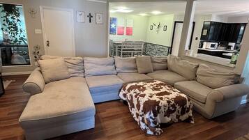 A living room with a sectional sofa, ottoman, and ceiling fan.