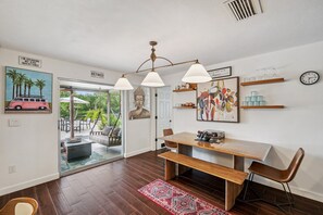 A modern dining area with a wooden table, benches, pendant lights, and artwork on the walls. - Clearwater Waterfront Escape w/ Private Pool (Clearwater)