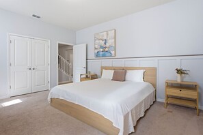 Ein Schlafzimmer mit Bett, Nachttisch, Wandbild und Tür.