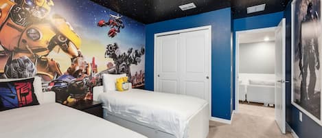 Un dormitorio con un mural de cielo estrellado, una puerta blanca y una cama con un cojín amarillo.