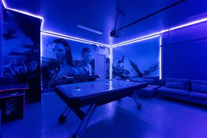Ein Zimmer mit Billardtisch, einer Couch und einer Projektionsleinwand.