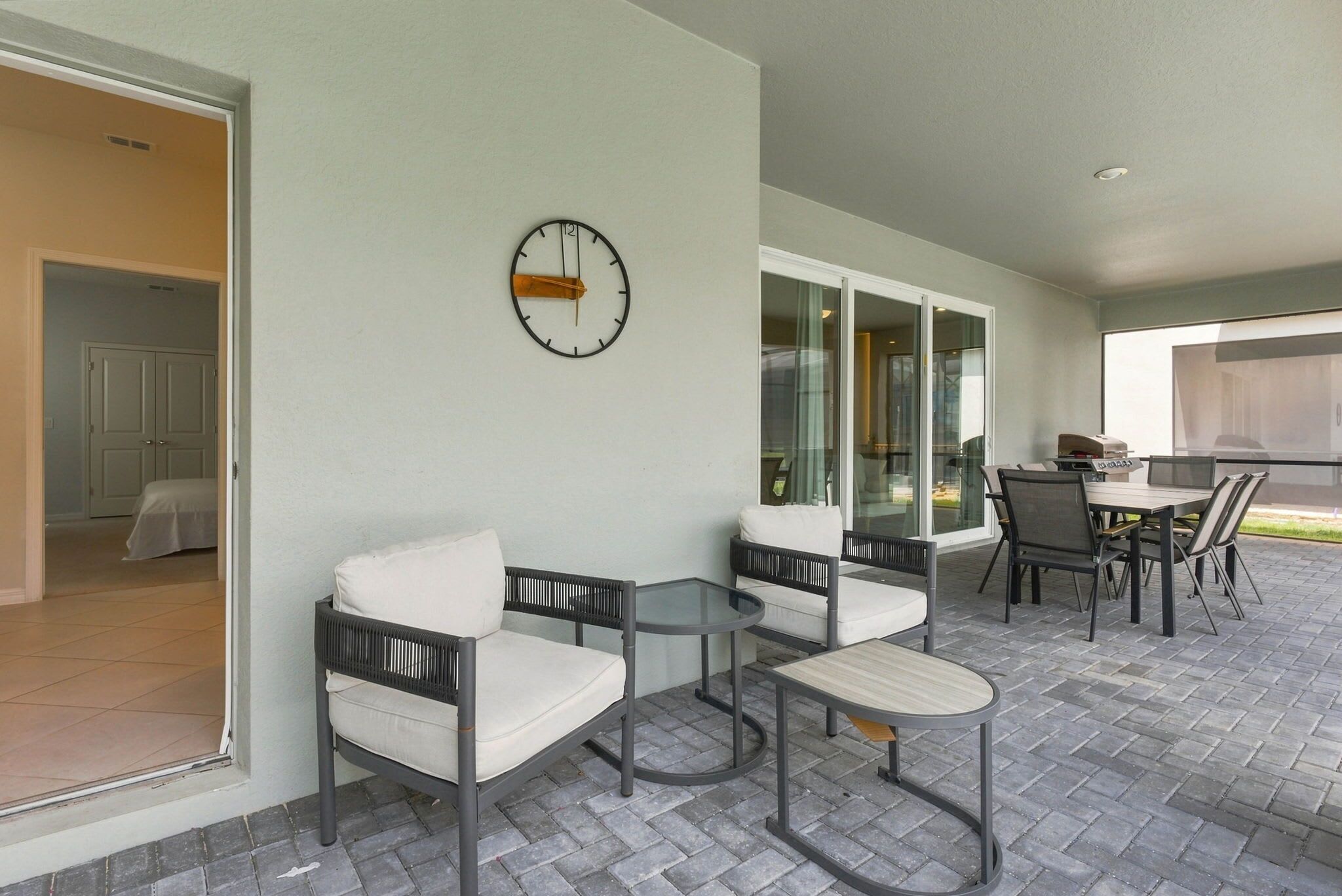 An outdoor patio area with a seating arrangement, a clock, and a view of the outside.