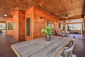 A wooden cabin with a dining area featuring a table and chairs, a potted plant, and a hot tub in the background. - Mountain Escape - Hot Tub, Fire Pit, Games & 3 Scenic Decks (Ellijay)
