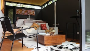 A modern living room with a sofa, a coffee table, and a chair. There is a painting on the wall and a window providing natural light. - Meular Chiloe B&B Hotel (Castro)