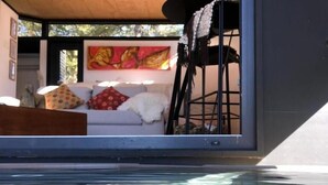 A modern interior with a pool, a sofa with cushions, and a painting on the wall.