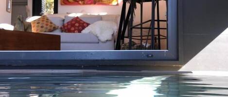Un interior moderno con una piscina, un sofá con cojines y un cuadro en la pared.
