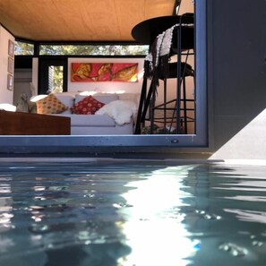 A modern interior with a pool, a sofa with cushions, and a painting on the wall.
