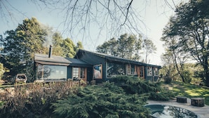 A cabin with a deck, surrounded by dense greenery and a small pond. - Meular Chiloe B&B Hotel (Castro)