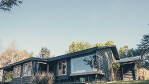 A modern house with a large glass window, a stone wall, and a grassy yard.