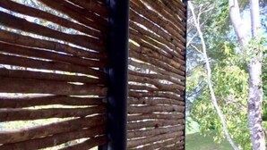 A wooden slatted structure with a view of a natural outdoor area.