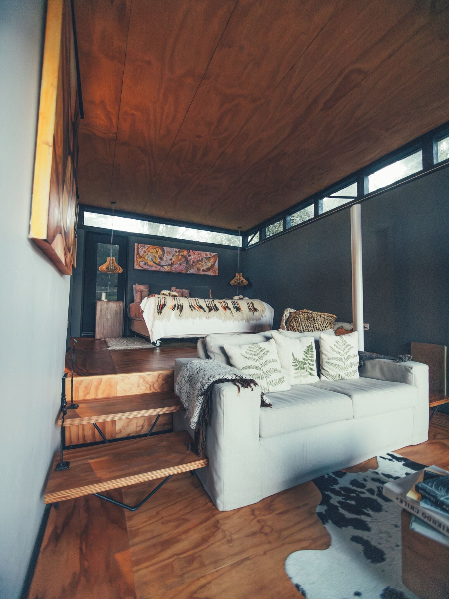 Una sala de estar moderna con un sofá, una cama y una escalera.