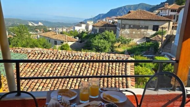 A table with breakfast items and a view of a village and mountains.