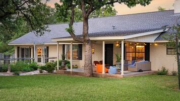 A house with a covered porch, a tree in front, and a well-maintained lawn.