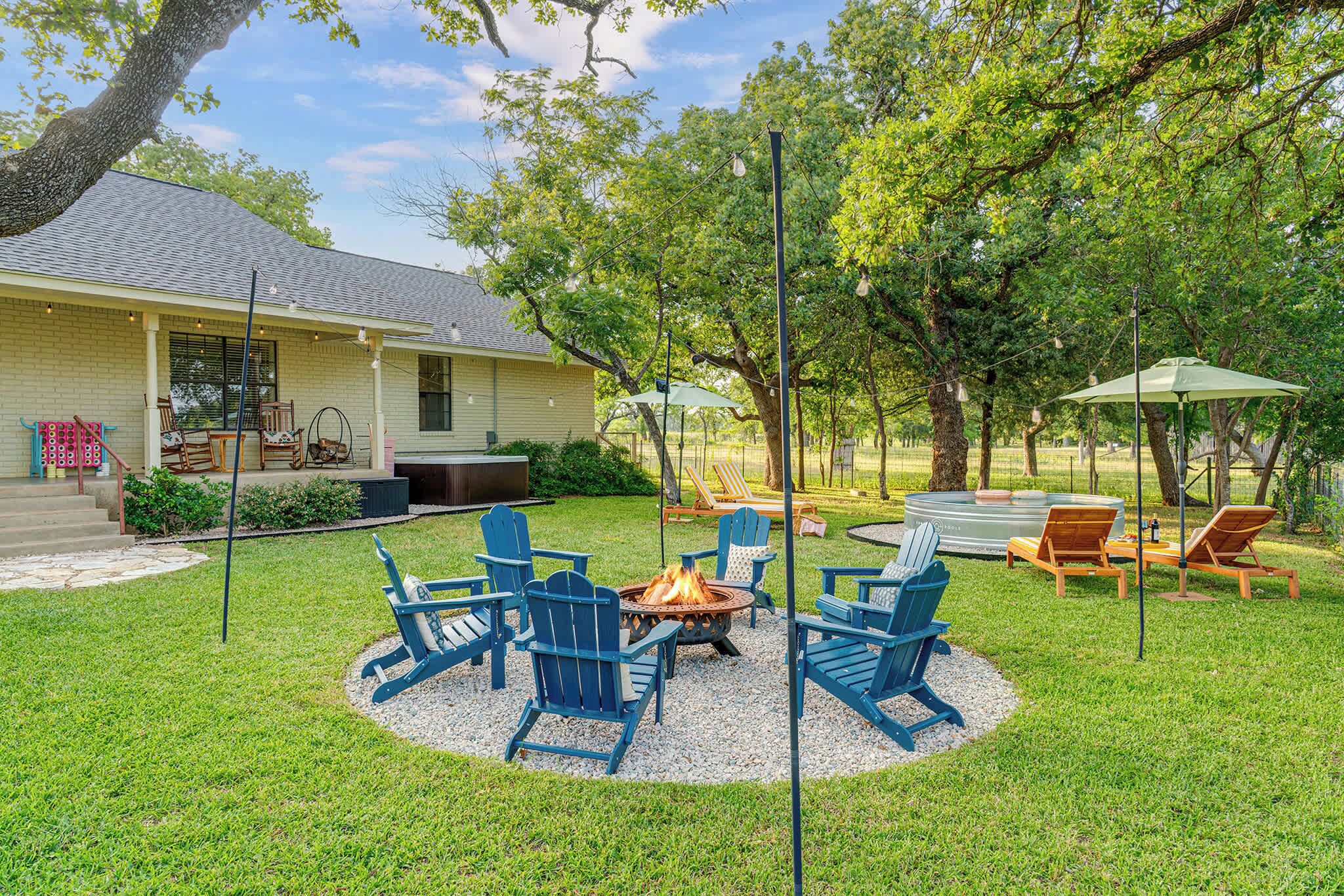 A backyard with a fire pit, outdoor furniture, and a house.