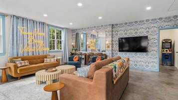 A living room with a sofa, ottoman, and a television.