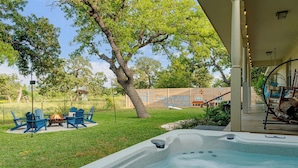 A hot tub with a fire pit, outdoor seating, and a covered area with a swing chair. - 290 Wine Trail, 2 Hot tubs, Cowboy Pool, Game Room (Fredericksburg)