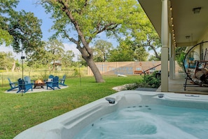 A hot tub with a fire pit, outdoor seating, and a covered area with a swing chair. - 290 Wine Trail, 2 Hot tubs, Cowboy Pool, Game Room (Fredericksburg)