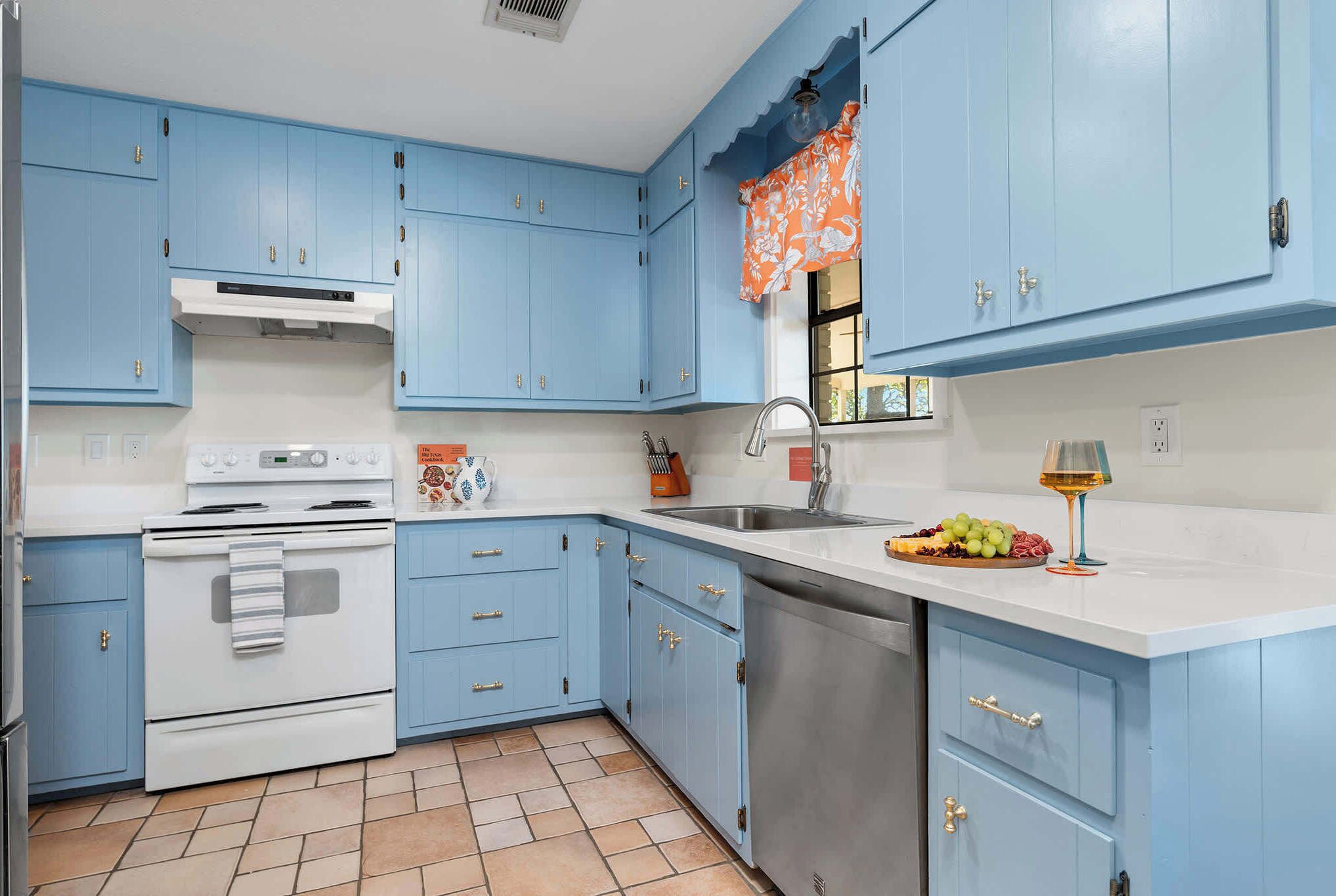 A kitchen with blue cabinets, a white stove, and a stainless steel sink.