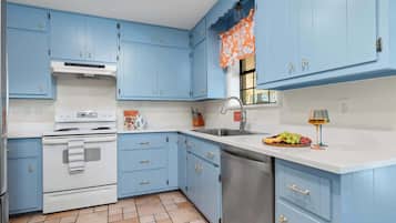 A kitchen with blue cabinets, a white stove, and a stainless steel sink.
