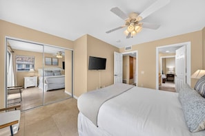 A bedroom with a bed, a ceiling fan, a TV, and a sliding door leading to a bathroom. - Pacific at your fingertips, best oceanfront views! (San Diego)