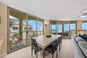 En modern inredning med ett matområde, en soffa och utsikt över stranden.