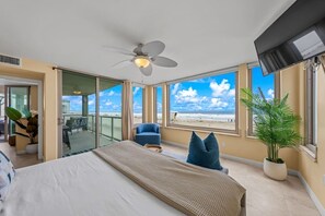 Ett hotellrum med en säng, en stol, en krukväxt och utsikt över stranden.