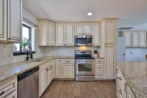 A kitchen with white cabinetry, a stainless steel oven, a microwave, and a dishwasher. - Beautiful home on 2 full acres with a pool! (Citrus Park)