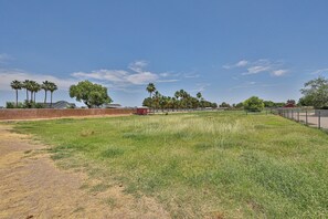 A fenced outdoor area with grass, trees, and a red structure. - Beautiful home on 2 full acres with a pool! (Citrus Park)