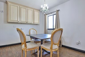 A dining area with a wooden table and four chairs, a chandelier, and a window with curtains. - Beautiful home on 2 full acres with a pool! (Citrus Park)