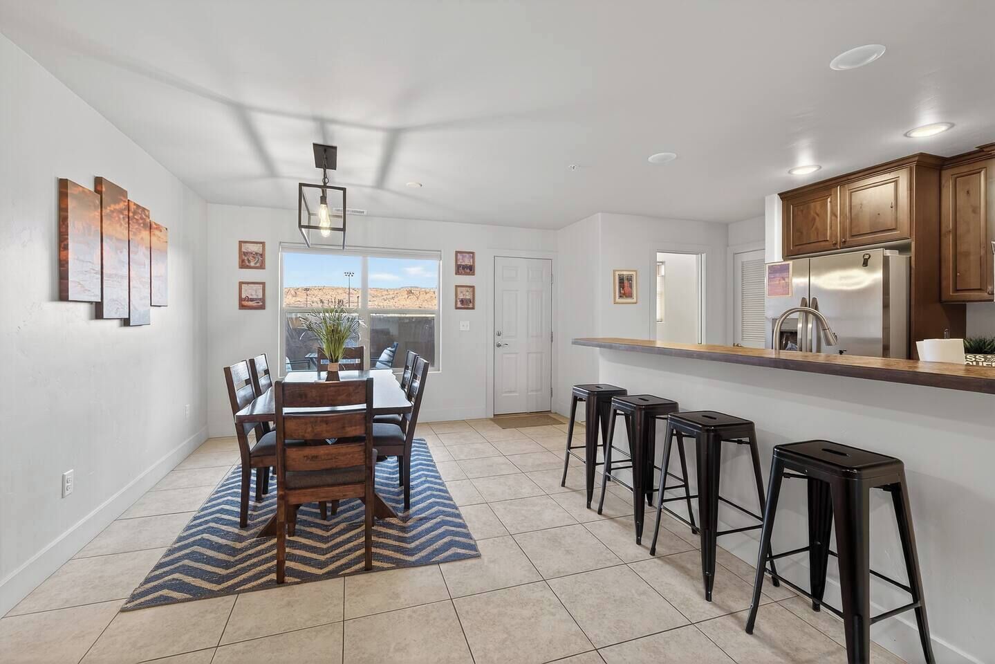 Una cocina moderna con barra, una mesa de comedor y sillas, y vistas al desierto por la ventana.