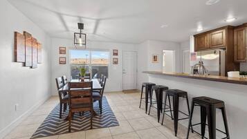Una cocina moderna con barra, una mesa de comedor y sillas, y vistas al desierto por la ventana.