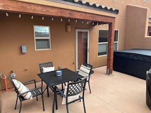 Eine Terrasse im Freien mit Tisch und Stühlen, einem überdachten Trampolin und einer Tür zum Haus.
