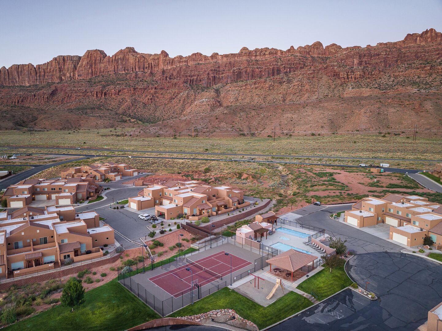 A residential area with modern buildings, a swimming pool, and a tennis court.
