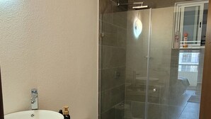 A bathroom with a white sink, toilet, and glass-enclosed shower. - Oaxtepec, Cocoyoc, or Tepoztlán—spacious and comfortable. 3 bedrooms, 2 bathrooms. 110 m (Oaxtepec)