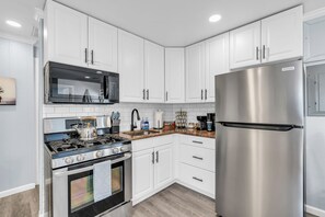Une cuisine moderne avec des meubles blancs, des appareils en acier inoxydable et un plan de travail en granit.