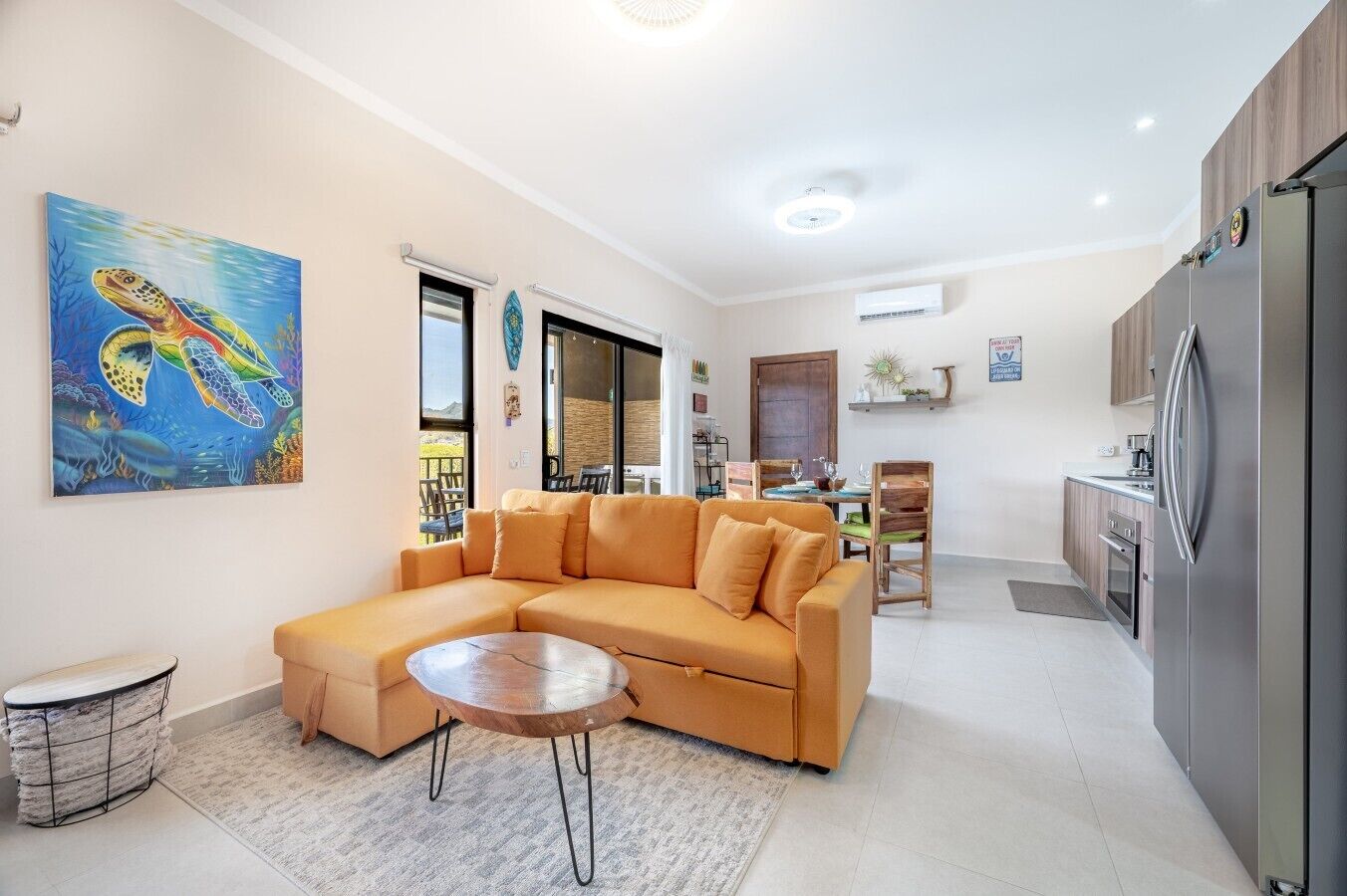 A modern living room with a sectional sofa, a round coffee table, and a painting of sea turtles.