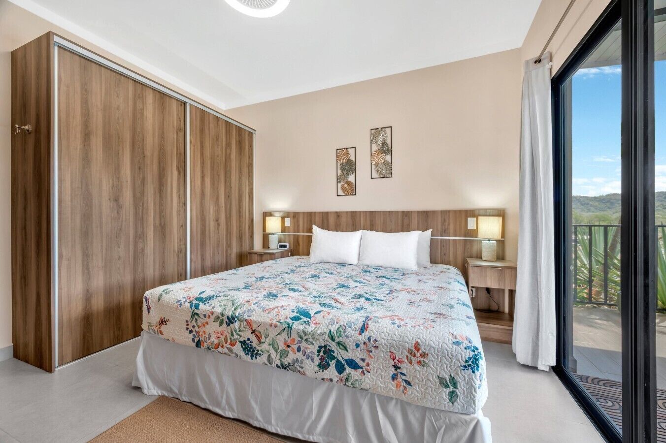 Une chambre avec un grand lit, une armoire, des lampes de chevet et une vue sur l’extérieur.